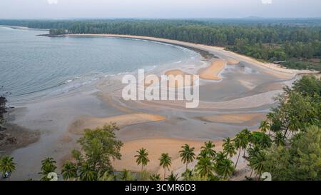 C'est une belle image de coucher de soleil sur l'océan, avec une petite île ou masse terrestre au premier plan. Les teintes dorées du soleil se fondent harmonieusement en t Banque D'Images