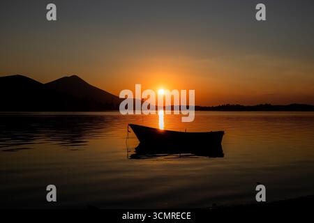 Bateau de pêche silhouetté au coucher du soleil sur la côte d'Evia, Grèce Banque D'Images