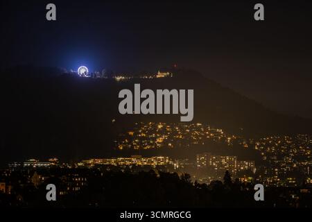 Berne, Suisse, paysage urbain la nuit, avec des bâtiments brillants et une grande roue sur une colline, soulignant la beauté des lumières de la ville et de l'encha Banque D'Images