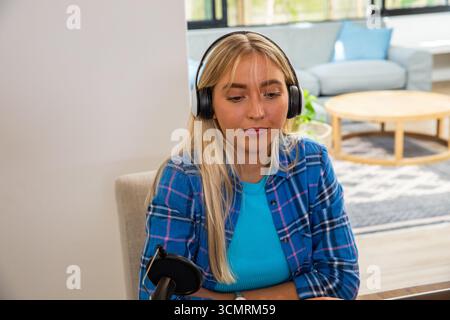 Femme enregistrant un podcast audio au bureau à domicile dans le salon avec microphone à filtre pop et écouteurs Banque D'Images