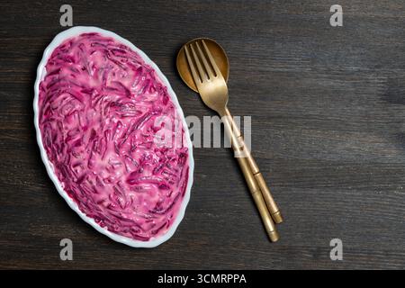 Salade ukrainienne traditionnelle dans une assiette appelée hareng sous un manteau de fourrure ou shuba sur une table en bois, gros plan, vue de dessus Banque D'Images
