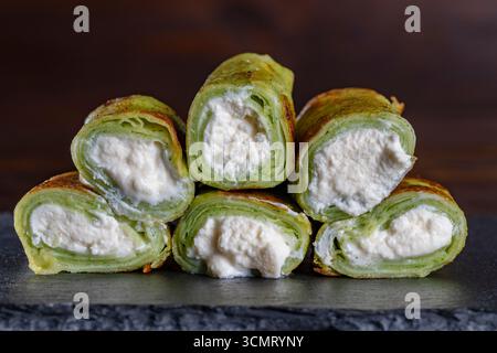 Rouleaux de printemps végétariens verts, crêpe aux épinards sur l'assiette, gros plan. Concept de petit déjeuner sain Banque D'Images