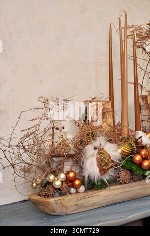 Élégante pièce maîtresse de Noël avec des bougies, des ornements, des branches de pin et des chouettes décoratives dans un plateau en bois naturel. Décoration festive de vacances pour confortable Banque D'Images