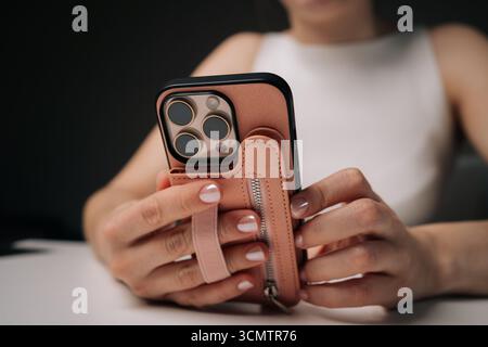 Femme tenant le nouveau téléphone portable avec étui élégant avec dragonne pratique, assurant une prise en main sûre tout en affichant un look à la mode et moderne. Banque D'Images