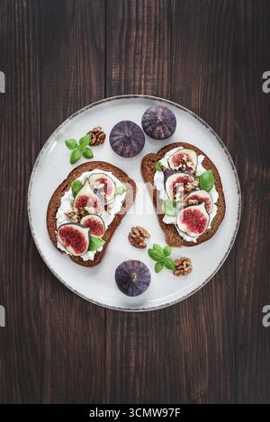 Sandwichs aux figues, fromage à la crème, basilic et miel sur fond de bois, vue de dessus Banque D'Images