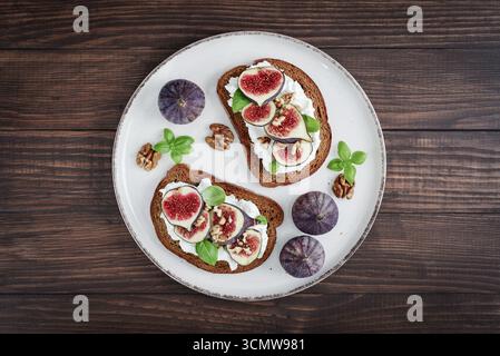 Sandwichs aux figues, fromage à la crème, basilic et miel sur fond de bois, vue de dessus Banque D'Images