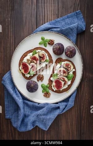 Sandwichs aux figues, fromage à la crème, basilic et miel sur fond de bois, vue de dessus Banque D'Images