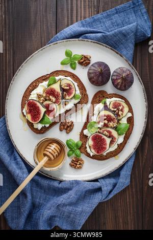 Sandwichs aux figues, fromage à la crème, basilic et miel sur fond de bois, vue de dessus Banque D'Images