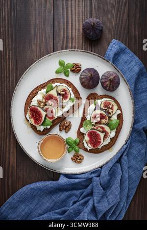 Sandwichs aux figues, fromage à la crème, basilic et miel sur fond de bois, vue de dessus Banque D'Images