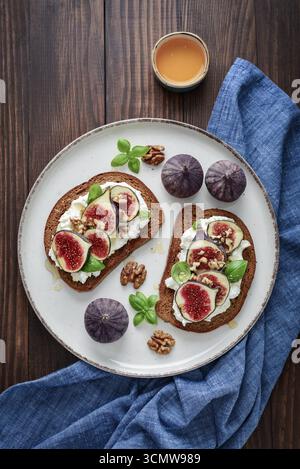 Sandwichs aux figues, fromage à la crème, basilic et miel sur fond de bois, vue de dessus Banque D'Images