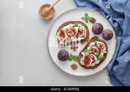 Sandwichs aux figues, fromage à la crème, basilic et miel sur fond clair, vue de dessus Banque D'Images