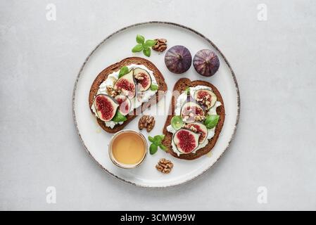 Sandwichs aux figues, fromage à la crème, basilic et miel sur fond clair, vue de dessus Banque D'Images
