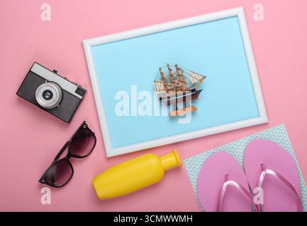 Accessoires de plage sur fond pastel rose avec cadre photo. Prise de vue en studio. Station balnéaire créative à plat, voyage. Vue de dessus. Minimalisme Banque D'Images