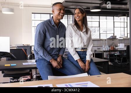 Divers collègues assis sur le bureau dans un bureau moderne ouvert avec fenêtres à panneaux de grille, moniteurs Banque D'Images