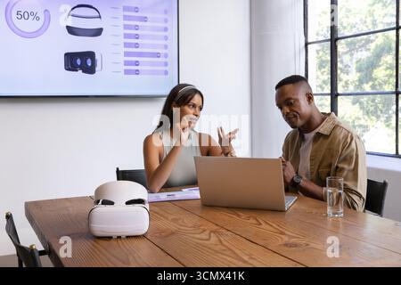 Divers collègues discutant du plan de projet à l'aide d'un ordinateur portable, casque vr dans la salle de conférence Banque D'Images