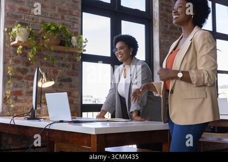Diverses collègues féminines discutant projet au bureau par bureau avec ordinateur portable et ordinateur portable Banque D'Images