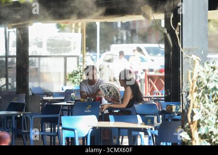 Madrid, Espagne. 17 septembre 2025. Les clients prennent leurs repas près d'un appareil de refroidissement à Madrid, Espagne, 17 septembre 2025. L'Agence météorologique d'État espagnole (AEMET) a déclaré qu'il fera plus chaud que d'habitude dans la plupart des régions jusqu'en septembre, car les températures dans certaines régions du sud devraient dépasser 38 degrés Celsius. Crédit : Gustavo Valiente/Xinhua/Alamy Live News Banque D'Images