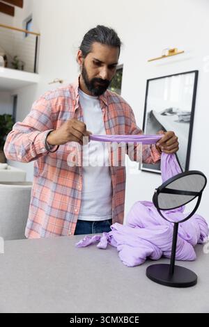 Homme indien tenant, étirant l'écharpe de lavande sur l'îlot de cuisine avec miroir de table Banque D'Images