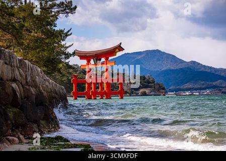 Vue panoramique de la porte flottante Torii du sanctuaire Itsukushima depuis un rivage rocheux sur l'île de Miyajima, au Japon Banque D'Images