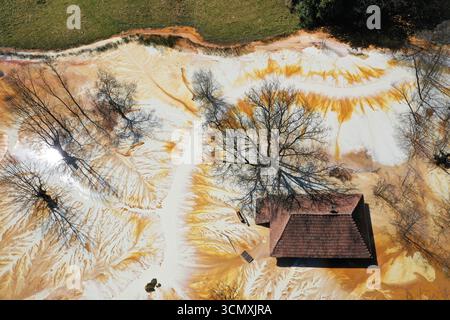 Vue aérienne de la maison de village en train de couler au milieu de l'étang de décantation de drainage de mine acide toxique. Geamana, Rosia Montana, Roumanie Banque D'Images