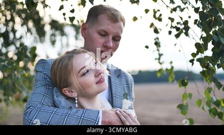 Couple de jeunes mariés embrassant sous le bouleau, profitant d'un moment romantique le jour de leur mariage Banque D'Images