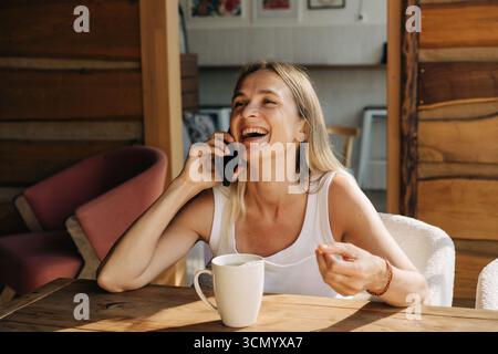 Heureuse belle blonde femme caucasienne parle sur un téléphone portable et rit. Banque D'Images