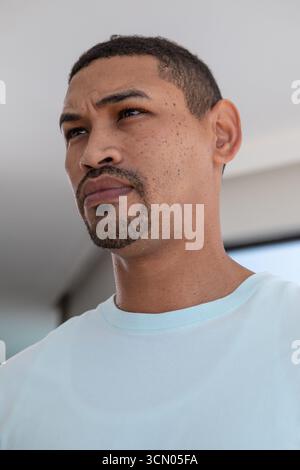 Homme d'âge moyen regardant soigneusement vers le haut vers la gauche tout en étant assis à la maison avec l'écran de télévision. Portrait, contemplatif, moderne, intérieur, professionnel, Banque D'Images