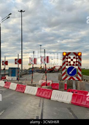Zone de construction, réparations de routes, panneau vous indiquant de tourner à gauche. Il y a des travaux en amont de la voie de contournement. Banque D'Images