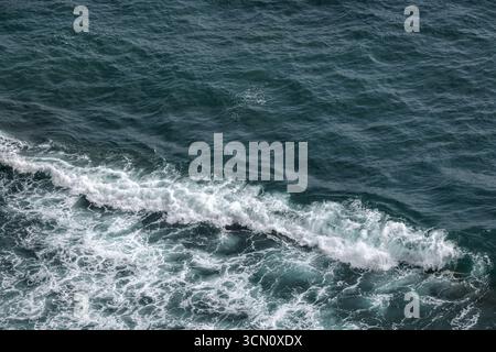 Vue aérienne sur l'océan montrant les vagues se brisant le long de la côte avec des eaux bleues vibrantes. Texture naturelle de la photo de fond Banque D'Images