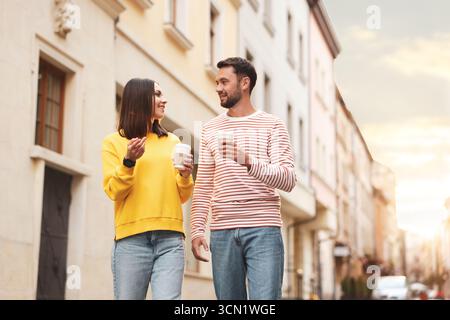 Café à emporter. Couple avec des tasses en papier de boissons marchant sur la rue de la ville, vue d'angle bas. Espace pour le texte Banque D'Images