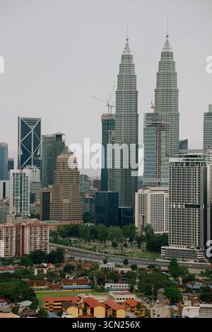 Kuala Lumpur, Malaisie - 22 janvier 2017 : horizon avec la majestueuse tour jumelle Petronas servant de repère architectural de la ville. Petits cottages confortables formant contraste avec les gratte-ciel sans vie Banque D'Images