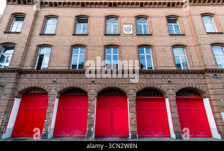 Vue de face de la caserne de pompiers du XIXe siècle (Feuerwache) à Prenzlauer Berg avec ses portes rouges emblématiques et sa façade en briques néo-romanes. Banque D'Images