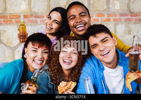 Jeunes amis divers mangeant de la pizza et buvant de la bière à la fête multiculturelle style de vie et amitié Banque D'Images