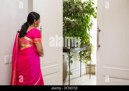 Les doubles portes à panneaux blancs s'ouvrent sur une pièce ensoleillée avec des plantes en pot en cascade Banque D'Images