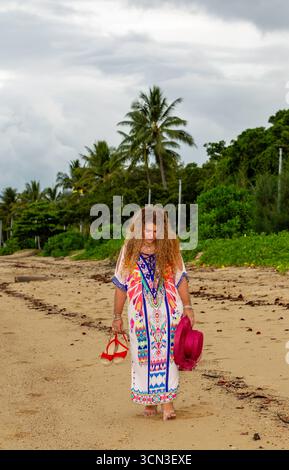 dame pensant orteil dans le sable walking plage couleur robe complète long cheveux bruns bouclés 50 plus modèles matures modèles australie australienne Banque D'Images