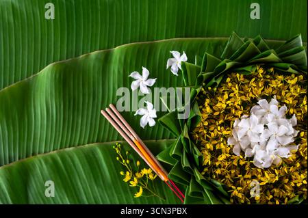 Krathong décore avec des fleurs qui ont flou l'accent de 3 bâtons d'encens et bougie mis sur la feuille de banane pour le festival Loy Krathong. Banque D'Images