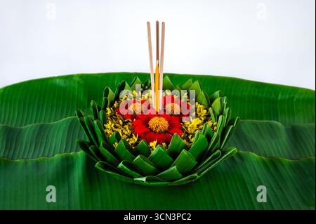 Krathong qui ont 3 bâtons d'encens et des décorations de bougie avec des fleurs rouges et jaunes met sur la feuille de banane pour Loy Krathong festival sur fond blanc Banque D'Images