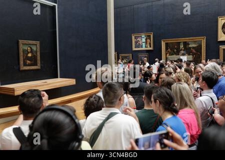 Paris, France - 9 juin 2023 : les touristes se rassemblent pour prendre des photos de la célèbre peinture de la Joconde de Léonard de Vinci à l'intérieur du musée du Louvre. Banque D'Images