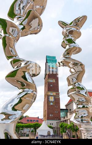 Darmstadt, Allemagne - 5 juin 2025 : des sculptures métalliques torsadées encadrent une vue sur la tour historique du mariage, mettant en valeur l'élégance architecturale et artis Banque D'Images