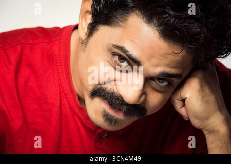Homme en chemise rouge avec expression réfléchie - Studio Portrait Banque D'Images