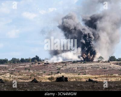 Explosions vues alors que des soldats d'infanterie polonais des Forces de défense territoriale s'entraînent à tirer à vue sous couvert lors de la journée médiatique Iron Defender 25. L’exercice Iron Defender 25 est l’événement d’entraînement le plus important et le plus important planifié par et pour les forces armées polonaises. Il s'agit d'une série d'exercices défensifs menés sur terre, dans les airs et sur l'eau par les forces terrestres, aériennes, navales, spéciales et territoriales de défense. Trente mille soldats et 600 pièces d'équipement des forces armées polonaises et des alliés de l'OTAN y participent. Banque D'Images