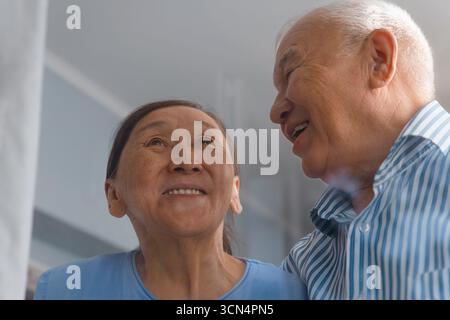 Heureux couple senior amoureux à la maison derrière la fenêtre Banque D'Images