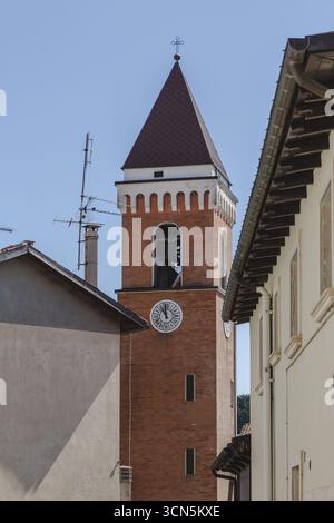 Vue d'une tour d'église en briques avec un toit rouge et une horloge s'élève au milieu des bâtiments sous un ciel bleu clair, Rivisondoli, Abruzzes, Italie. Banque D'Images