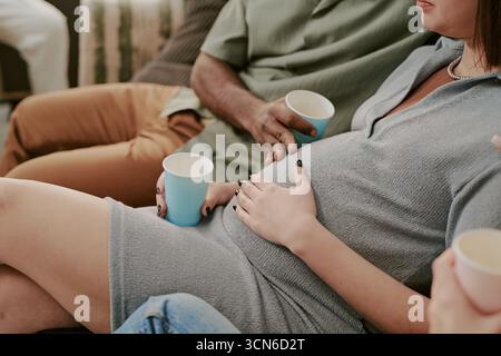Enceinte jeune adulte femme caucasienne se relaxant avec des amis à social Gathering Banque D'Images