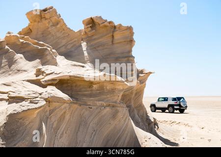 Émirats arabes Unis - Abu Dhabi - Al Wathba Fossil Dunes - pâles formations s'élèvent au-dessus des appartements ouverts tandis qu'un 4x4 s'arrête à proximité, révélant l'échelle dans le deser sauvegardé Banque D'Images
