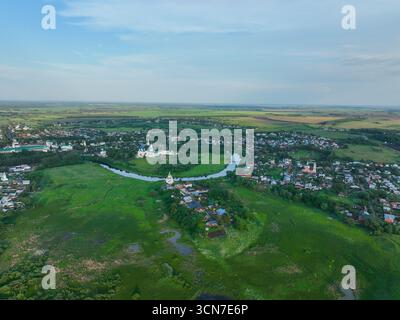 Une large vue aérienne de la ville de Souzdal, montrant la rivière Kamenka serpentant à travers la zone urbaine et deux monastères historiques. Banque D'Images