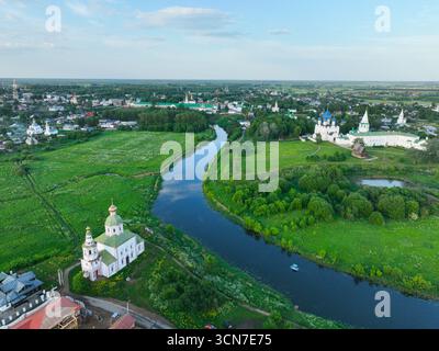 Une large vue aérienne de la ville de Souzdal, montrant la rivière Kamenka serpentant à travers la zone urbaine et deux monastères historiques. Banque D'Images