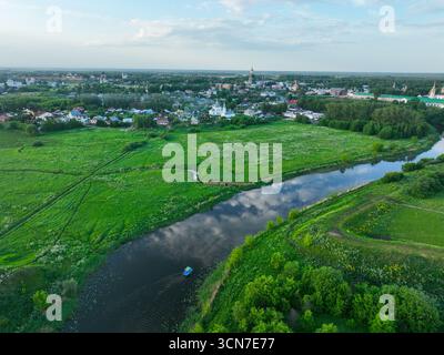 Une large vue aérienne de la ville de Souzdal, montrant la rivière Kamenka serpentant à travers la zone urbaine et les monastères historiques. Banque D'Images