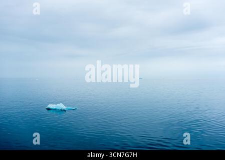 Iceberg à Klerckbukta Nordaustlandet Svalbard Norvège // NORDEAUSTLANDET, SVALBARD, NORVÈGE — un iceberg flotte dans les eaux calmes et bleues de Klerckbukta, une baie située sur Nordaustlandet, la deuxième plus grande île de l'archipel du Svalbard. Nordaustlandet se caractérise par ses vastes calottes glaciaires et ses paysages glaciaires. L'archipel du Svalbard est situé dans l'océan Arctique, à peu près à mi-chemin entre la Norvège continentale et le pôle Nord. Ces îles sont connues pour leur environnement arctique extrême, abritant une faune et des formations géologiques uniques. Klerckbukta fait partie du nord-est du Svalbard Natu Banque D'Images