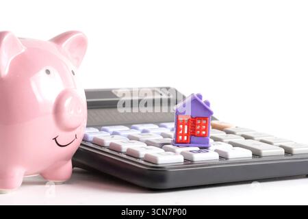 Tirelire rose avec calculatrice et maison sur fond blanc Banque D'Images